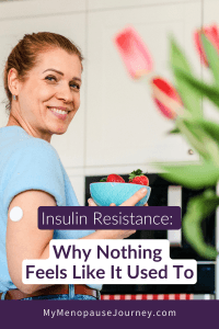 Smiling midlife woman in her kitchen holding strawberries with a glucose monitor on her arm &mdash; insulin resistance in women
