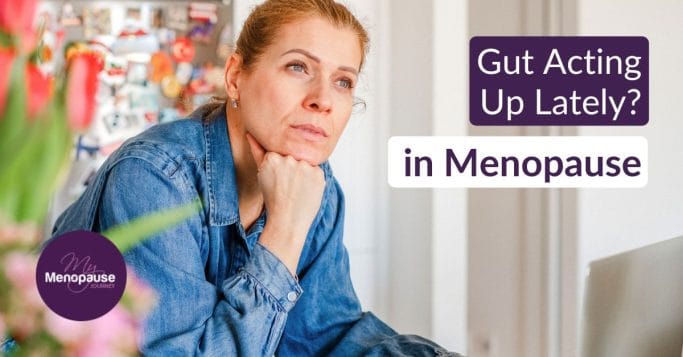Thoughtful midlife woman in a denim shirt in her kitchen, wondering about IBS in menopause